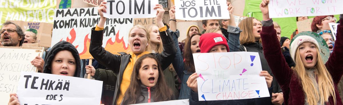 Lasten ja nuorten joukko pitelee kylttejä ja huutaa iskulauseita mielenosoituksessa.