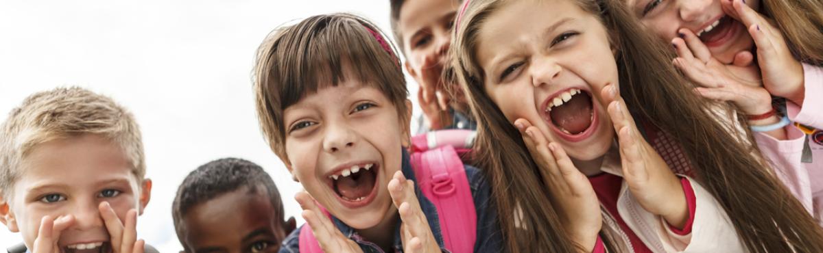 Joukko alakouluikäisiä lapsia huutaa jotain naurussa suin. 
