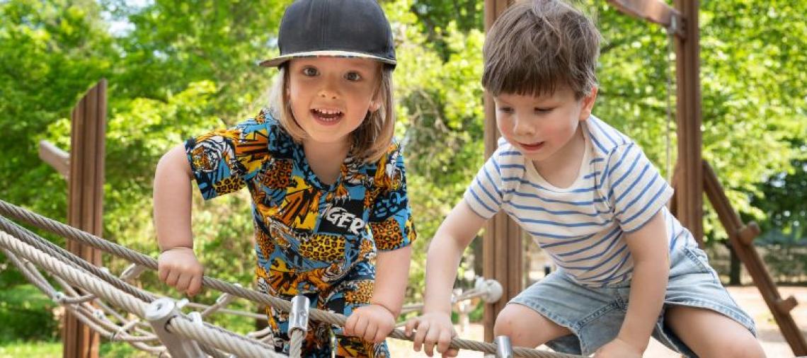 Leikki-ikäiset lapset kiipeilevat kiipeilytelineessä. 